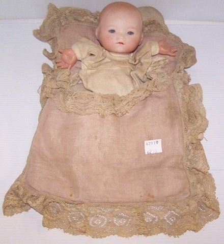 *A.M. DREAM BABY PUPPET: Bisque baby in a blanket, having set blue eyes with closed mouth, on cloth body with celluloid hands,