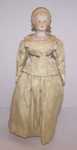 *BISQUE HEAD DOLL: Having painted features with molded blonde hair and earrings, on cloth body with bisque arms and legs with painted on boots, approximate height 11 1/2".