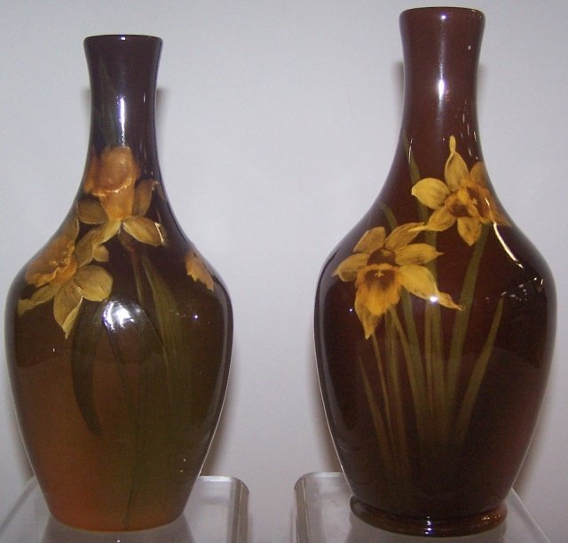 *2 ROOKWOOD ART POTTERY VASES: Bottle form, decorated by Josephine E. Zettel with yellow daffodils on a brown, green and rust ground, marks include impressed Rookwood flame logo indicating date 1898, shape #744 C, process mark, sig