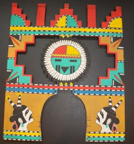 *HOPI TABLITA: Tawa Sun Kachina face with Hano Clowns on front and corn stalks on back, approximate height 16 1/2", width 14".