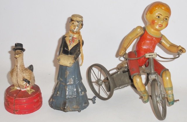 *TWO WIND-UP TOYS: Child on tricycle, approximate height 8 3/4", woman, height 7 5/8", along with a cast iron bank, duck with top hat and umbrella, reading "Save for a rainy day", height 5 3/8".