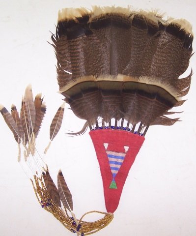 *CROW FAN: Having red wool handle with beaded design, holding 10 feathers and beaded yellow, white and blue strands with miniature feathers, approximate height 26".