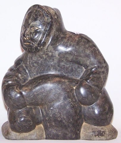*INUIT CARVED SOAPSTONE SCULPTURE: Neokuk man with fish, artist signed on bottom "Abraham", approximate height 8".