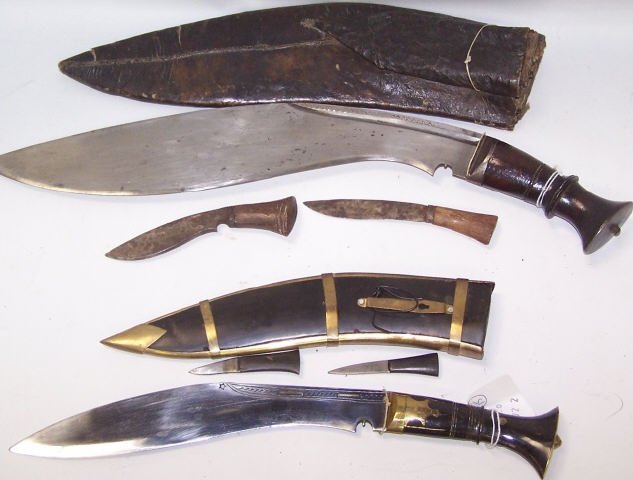 *2 NEPALESE KUKRI KNIVES: 1 with plain blade, no markings, with carved horn handle, leather scabbard with 2 small knives, and 1 with partially engraved blade, no maker, with carved horn handle having brass mountings, carved ho