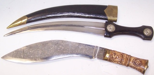 *2 NEPALESE KUKRI KNIVES: Steel blades, 1 having carved bone handle with brass mounts, engraved blade, 1 having carved wood handle with silver metal mounts, wood scabbard with brass mounts.