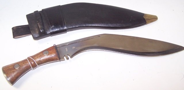 *NEPALESE KUKRI KNIFE: Steel blade stamped "India", having carved wood handle with silver metal mounts, leather scabbard with brass mounts, approximate length 18".