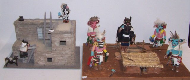 *2 DIORAMAS: Hopi Adobe house diorama with clay masked woman and carved and painted wood kachina depicting dancer and a Native American diorama with Kiva roof, having 5 carved and pained wood kachinas.