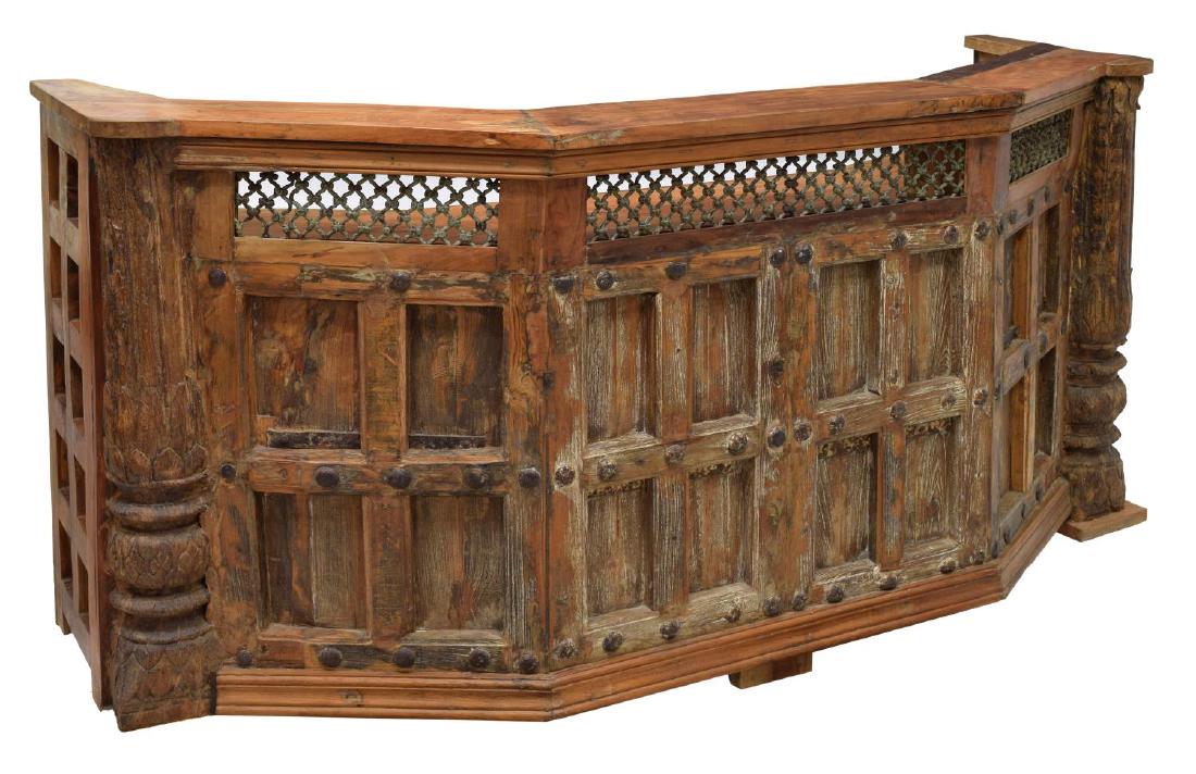 COLONIAL CARVED TEAK & WROUGHT IRON CLUB BAR: Teakwood club bar, having an upper shelf over pierced iron lattice panels, above work surface, fitted with two drawers, stemware holders, and bottle racks, approx 41"h, 85"w, 31.5"d Start Price: $450.
