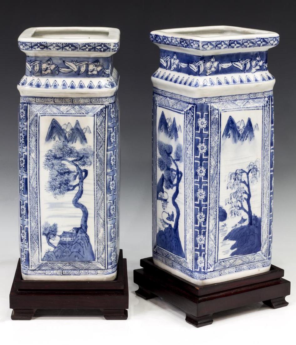 (2) CHINESE BLUE & WHITE PORCELAIN SQUARE VASES: (lot of 2) Chinese blue and white porcelain vases of square form, each with mountainous landscape reserves, blue character marks underfoot, accompanied by wood stands, overall: approx 15.75"h, 6.5"w, 