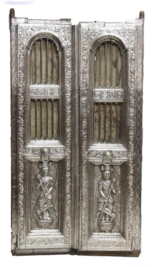 SILVER CLAD TEMPLE DOOR, INDIA, 99% PURE SILVER: Jain temple door set, India, c. 1900, covered in silver repousse worked sheeting with foliate and various Jainism religious symbols including swastika, the fish couple and the throne, vertical silver 