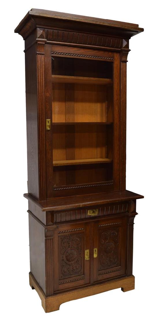 DANISH CARVED OAK GLAZED TWO PART CUPBOARD: Danish carved oak cupboard, having a corniced top over grooved trim, above the beveled glass panel door, opening to shelved interior, above lower case fitted with single drawer and double doors concea