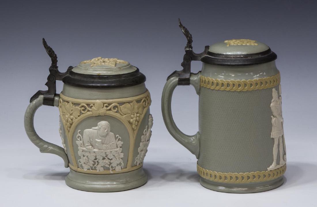 (2) VILLEROY & BOCH METTLACH STEINS, #1266, #2931: (lot of 2) Villeroy & Boch Mettlach relief beer steins: #1266, 1/2L, c. 1896, panels showing various seated drinking figures, overall grape motif, inlay top with pewter rim and grape bunch thumb rest,
