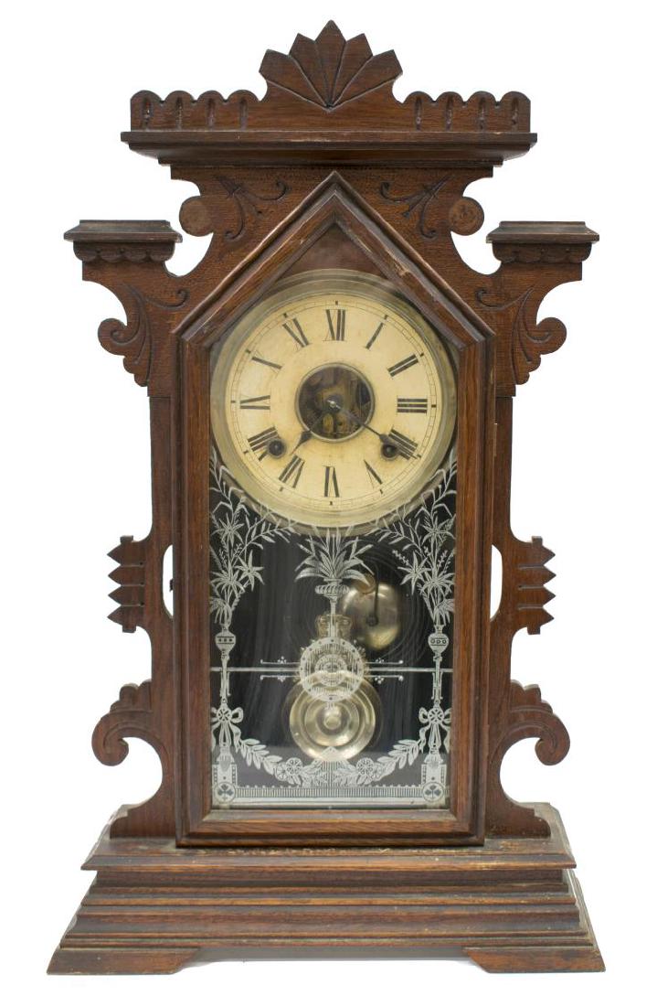 ANSONIA WALNUT KITCHEN CLOCK: American Ansonia walnut kitchen clock,`9th c., gilt designs at the glass door over the time and strike movement with Roman numerals, the case with Eastlake carving, operating, 22.5"h, 13.5"w, 5"d, 6lb