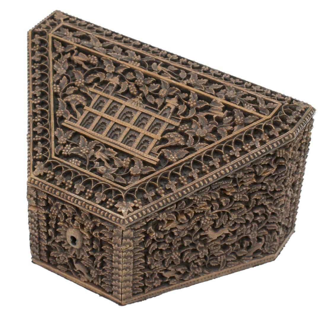 INDIA MIHRAB ARCHITECTURAL FINELY CARVED TABLE BOX: Profusely carved table box of trapezoidal form, India, the whole carved with trailing berry vines, fronted by small lock (lacking key), lift top centering a building carved with repeated mihrab arches