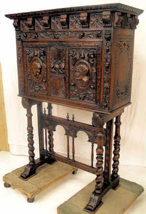HIGHLY CARVED VARGUENO DESK SPAIN: A highly carved vargueno from Northern Spain. Based upon a colonial style travel desk, the front is carved with soldiers, a double eagle shield, other faces and carved floral. The sides bear incised c
