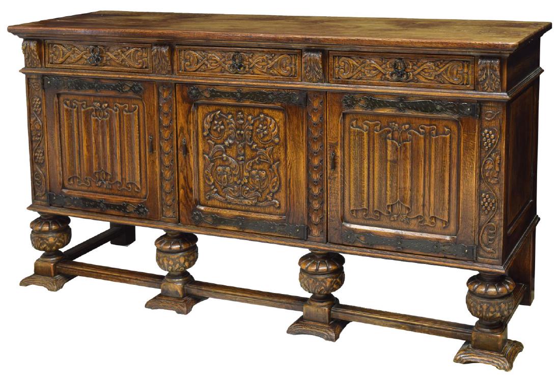 FRENCH GOTHIC REVIVAL OAK SIDEBOARD, 19TH C.: French Gothic revival oak sideboard, 19th c., having three drawers over three cabinets, with metal hardware and decorative hinges, highly carved door and drawer panels, including acorn and scroll desi
