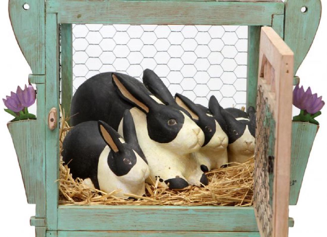 VINTAGE FOLK CARVED BUNNY HUTCH WITH RABBITS: Vintage folk art bunny hutch, painted green and pink wood framed hutch, leather hinged door opening to four wood bunnies, metal floral accents, rising on conforming stand, hutch and each bunny signed 