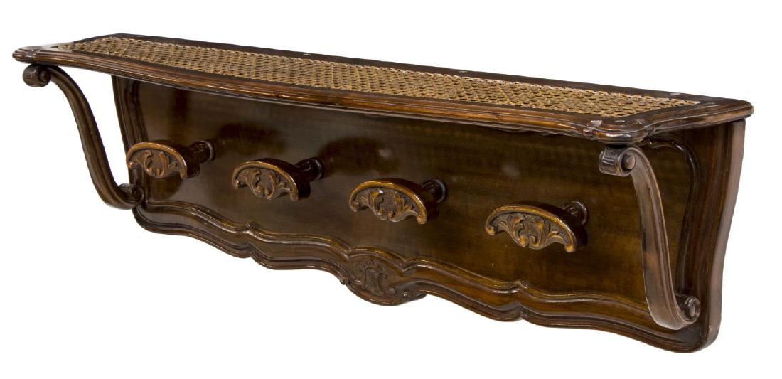 VINTAGE CONTINENTAL WOOD & CANED WALL HAT RACK: Continental hanging hat rack, 20th c., the shaped caned shelf supported by scrolling arms over the carved wood back, issuing four scrolling foliate knobs, some surface scratches, 12"h, 38.5"w, 7.75"d,