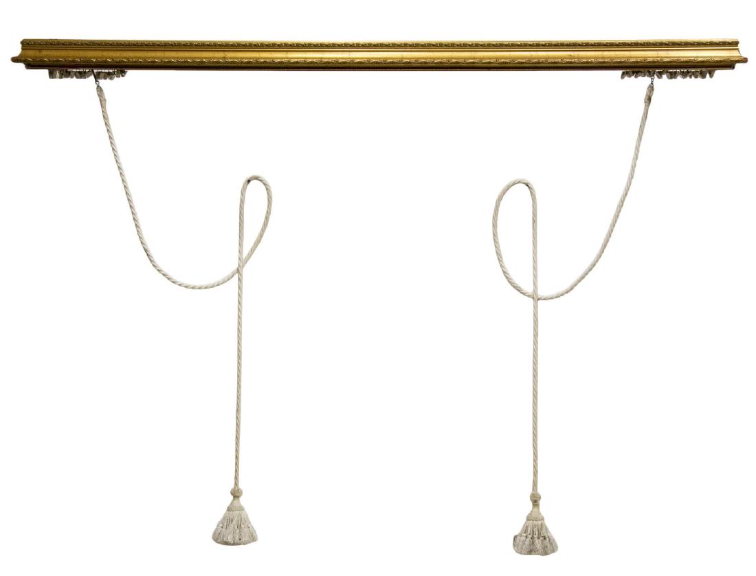 ITALIAN CARVED GILTWOOD CURTAIN VALENCE: Italian giltwood curtain cornice valence, 20th c., valence carved in the form of crown molding, cornice having scrolled foliate trim, retaining curtain track clips and tassels, some gilt loss and disc