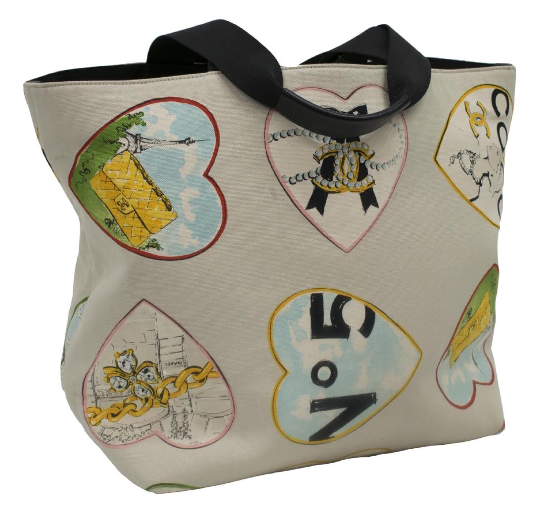 LARGE CHANEL HEARTS PRINT CANVAS TOTE BAG: Large Chanel tote bag in beige canvas with multicolor hearts print design, dual black top handles above top opening to lined interior with two zippered pockets, on CC black rubber square feet, some st