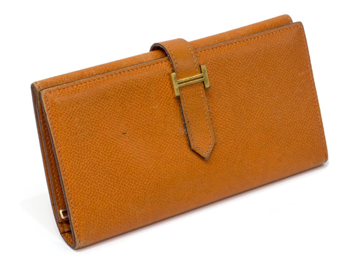 HERMES 'BEARN' GRAINED ORANGE LEATHER LONG WALLET: Hermes "Bearn" tri fold long wallet in grained orange leather, gold tone hardware, slip leather tab opening to interior with a full length zippered pocket and a bill compartment on one side, card slot