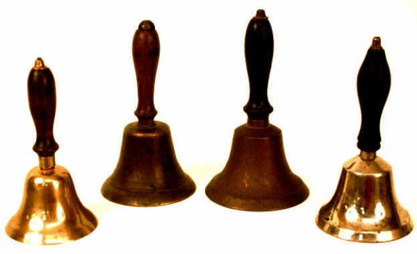 FOUR OLD SCHOOL TEACHER BELLS: A group of four old school teachers desk bells, all with wood handles. One about 6.5'H x 3.25"D, one about 6.5"H x 3.5"D, one about 7"H x 4"D, one about 6"H x 3"D and 2lbs combined.