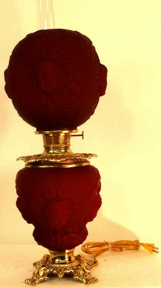 NEW RED GONE WITH THE WIND LAMP: A Gone With the WInd styled lamp, new, with red shade and base on brass. Cherub faces on glass. About 27"H x 9"w x 9"D and 9.5lbs.