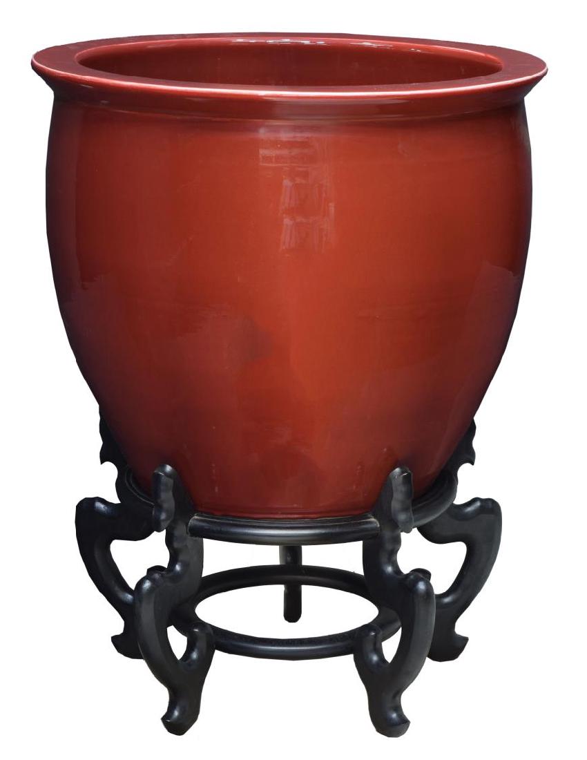 CHINESE SANG DE BOEUF OX BLOOD FISH BOWL & STAND: Chinese Sang de Boeuf porcelain fish bowl, in ox blood red, accompanied by carved hardwood stand, approx 32.75"h, 25"d Start Price: $150.00