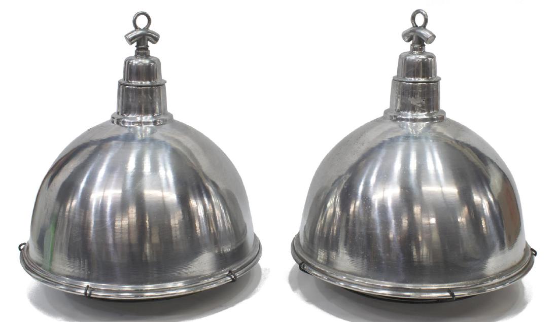(2) INDUSTRIAL STYLE ALUMINUM HANGING LIGHTS: lot of 2) Vintage Industrial style domed aluminum hanging lights, each with iron cage cover, one with small socket, one lacking socket, both in need of rewiring, some spotting, small dents, approx 19"