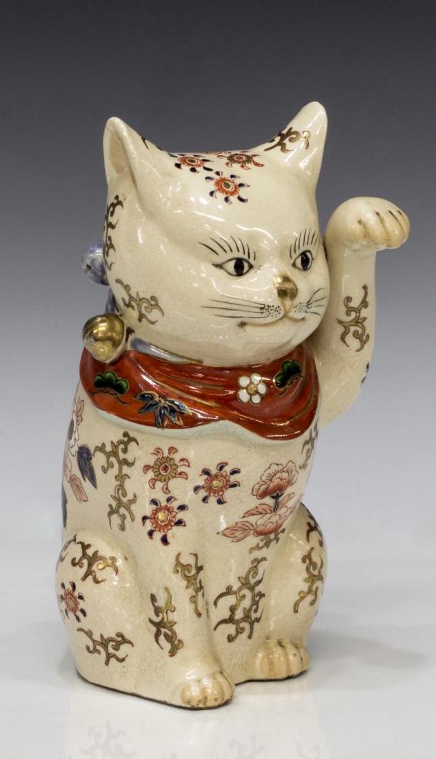 JAPANESE KUTANI IMARI MANEKI NEKO BECKONING CAT: Japanese Kutani Imari Maneki Neko beckoning cat, having white body, with traditional Imari patterns, wearing red scarf with gilt bells, red character mark on bottom, 9"h, 3.75"w, 5.25"d, 2lbs **Proven