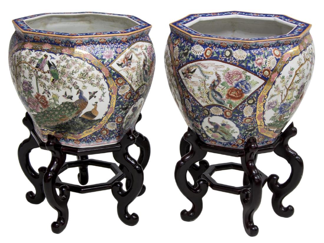 (2) CHINESE FAMILLE ROSE EIGHT-SIDED FISH BOWLS: (pair) Chinese famille rose enameled porcelain eight-sided fish bowls, having carved wooden stands, flared rim over tapered body, parcel gilt, bowl exterior with floral design and medallions featuring