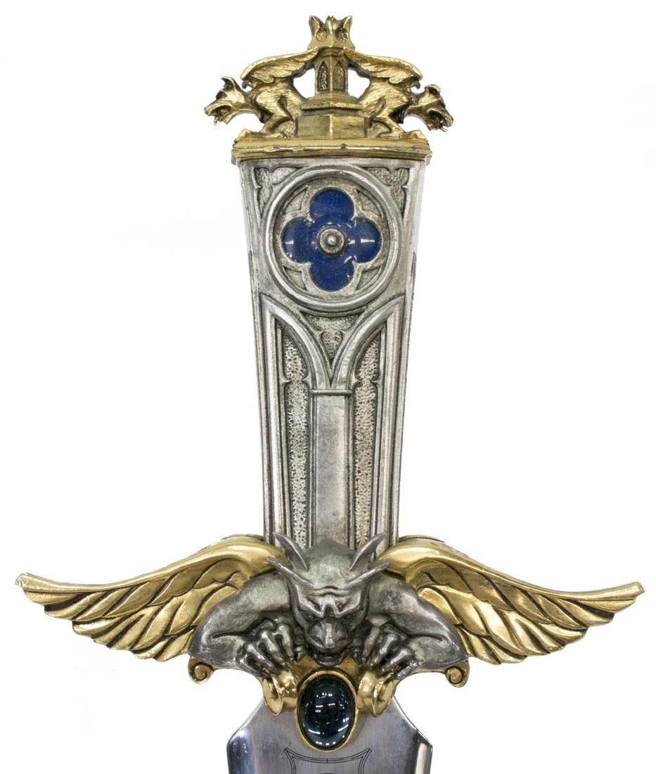 PATINATED STEEL WINGED GRIFFIN FANTASY DAGGER: Heavy patinated steel fantasy dagger, etched blade surmounted by a hilt with winged griffins and blue cabochon, blue enameled floriform accent to top, approx 14.5"l, Start Price $20.00