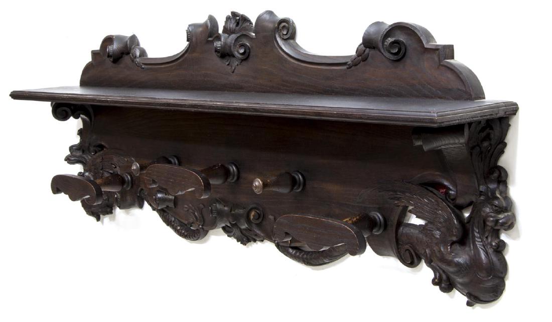 ITALIAN HANGING COAT & HAT RACK CARVED GRIFFINS: Italian oak wall mounted coat and hat rack, late 19th c., having cornice shelf, with scroll crown, over coat and hat pegs, with carved winged griffins, some loss to carving, 25"h, 64.5"w, 8.25"d Start