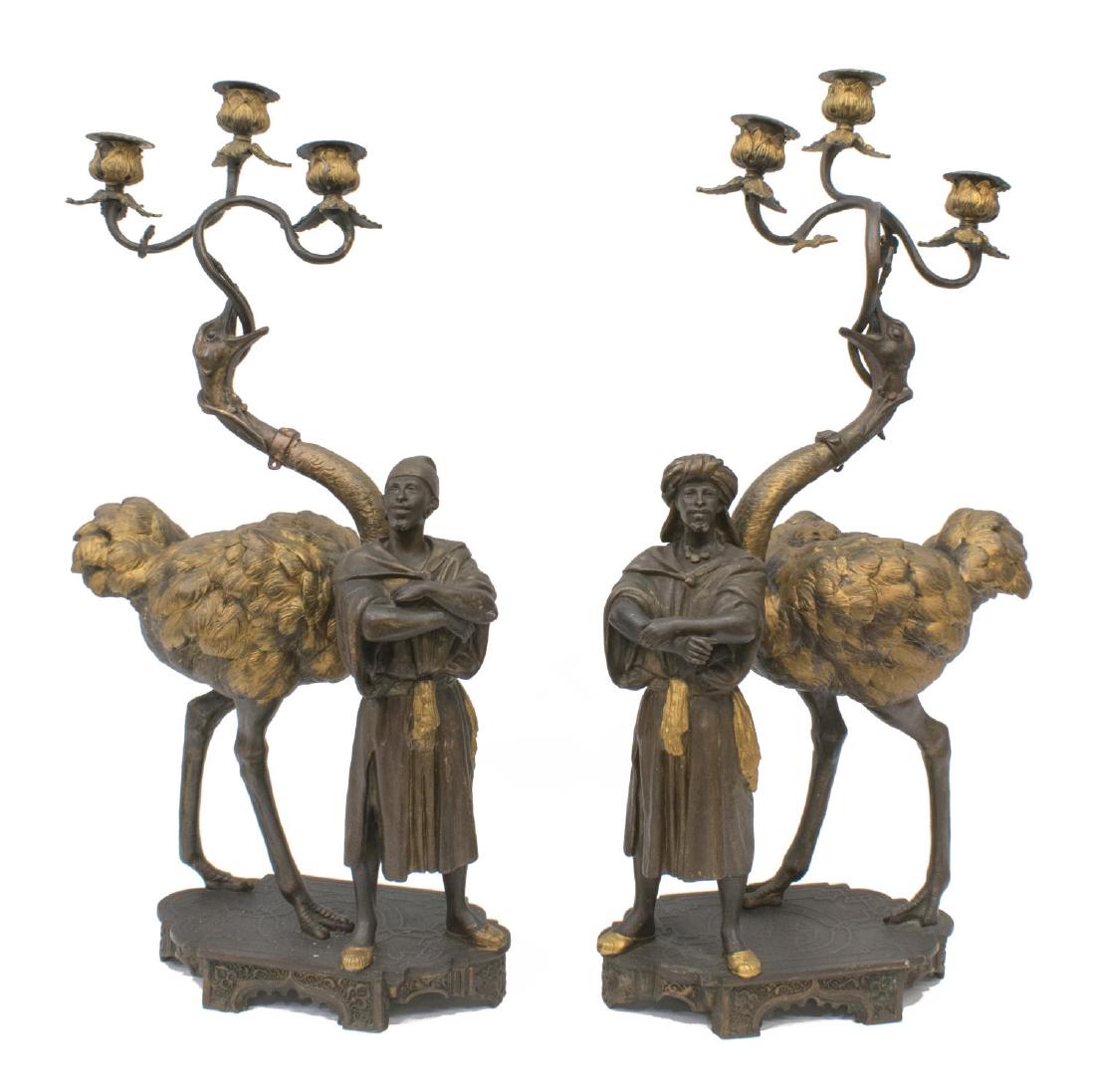 (PAIR) ORIENTALIST OSTRICH THREE-LIGHT CANDELABRAS: (pair) Orientalist candelabra, Continental, 19th c., patinated metal, having Moorish figure, with standing ostrich holding scrolled foliate-cast branches in its beak, with three conforming bobeches an