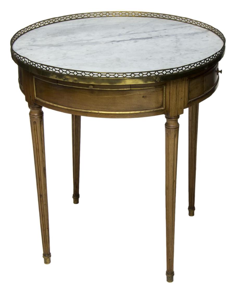 FRENCH LOUIS XVI STYLE MARBLE TOP GUERIDON: French gueridon, early 20th c., the circular marble top surrounded by a short pierced brass rail above two frieze drawers, rising on tapered ribbed legs, 28.25, 25.5"diameter Start Price: $150.00