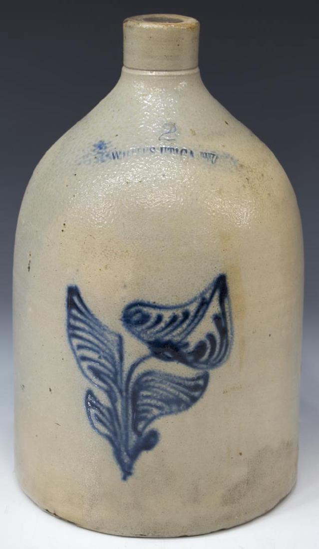 WHITES UTICA, NEW YORK STONEWARE 2-GAL LILY JUG: American salt-glazed stoneware two-gallon jug, Utica, New York, c. 1860, stamped Whites (Noah White Pottery), with pulled strap handle, cobalt slip design of a calla lily at front face, approx 15"h, 9