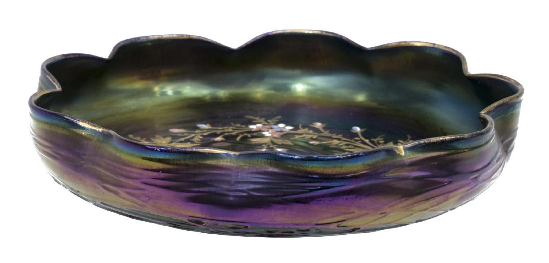 IRIDENSCENT PARCEL GILT ENAMELED ART GLASS BOWL: Iridescent violet art glass low bowl, possibly Loetz, undulating wavy rim over threaded exterior base, the smooth interior having brightly gilt and raised enamel flowering vines, approx 1.75"h, 8.75"d