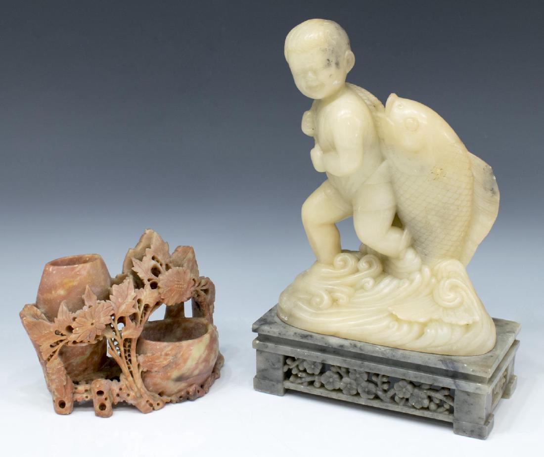 (2) CHINESE SOAPSTONE CARVINGS, LARGE FISHER BOY: (lot of 2) Chinese soapstone carvings: (1) large sculpture, young boy with fish on string, emerging from the waves, on a mottled gray base carved to the front with a pierced floral panel, small chip t