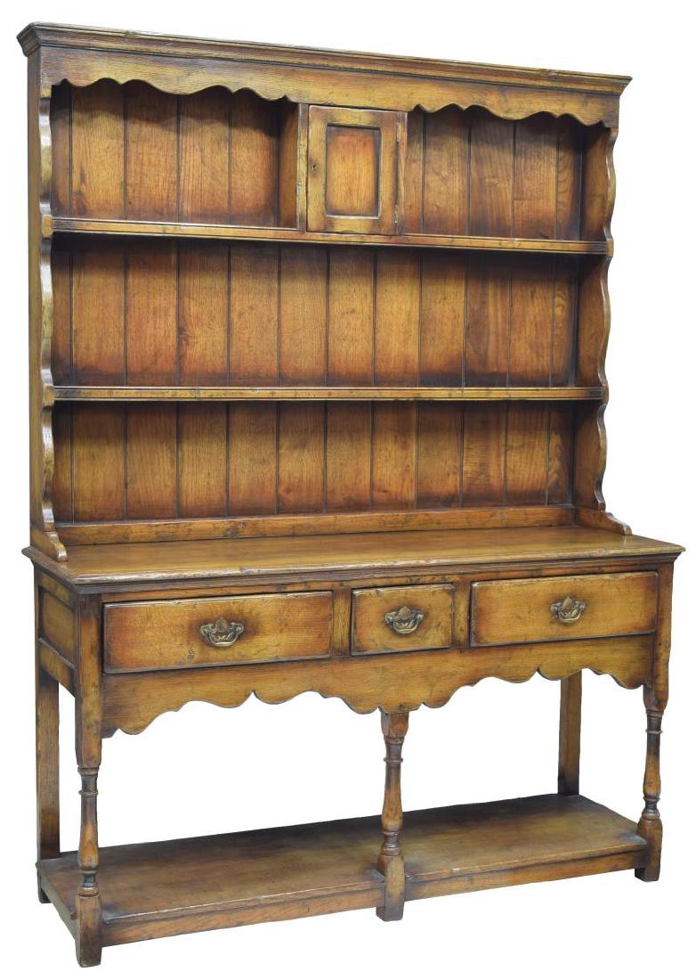 CARVED OAK WELSH CUPBOARD / SIDEBOARD: Carved oak Welsh cupboard, a stepped cornice over the two shelf display back housing a small dingle door cabinet, the lower work surface above three frieze drawers, rising on turned supports joined by