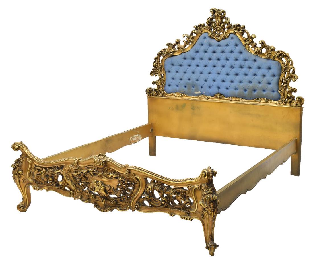 ITALIAN LOUIS XV STYLE HEAVILY CARVED GILT BED: Italian Louis XV style heavily carved gilt bed, having pierced and carved scroll and foliate head board, surmounted with winged cherub crest, holding tufted fabric upholstery, heavily carved footboard