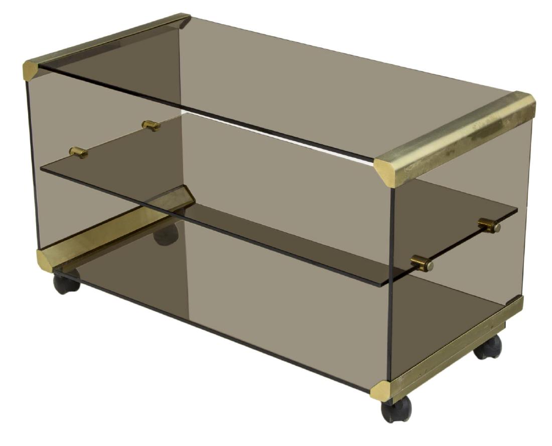 ITALIAN MODERN BRASS & SMOKE GLASS BAR CART TABLE: Italian modern bar cart table, c. 1970s, brass frame, supporting three tiers of smoke glass shelves, on casters, approx 19.25"h, 32"w, 16"d Start Price: $150.00