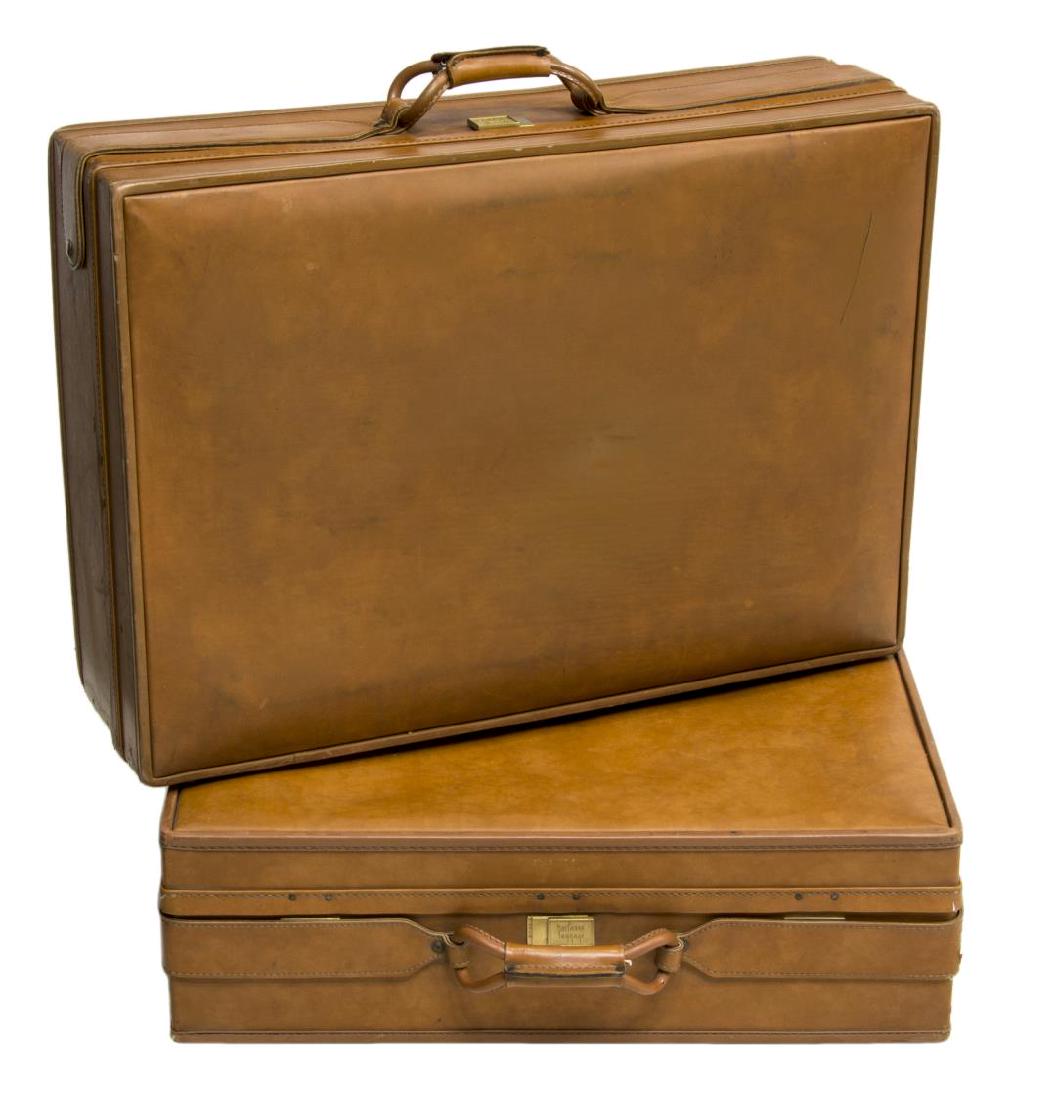 (2) HARTMANN LUGGAGE ORANGE LEATHER SUITCASES: (lot of 2) Orange leather suitcases, c. 1960s, by Hartmann Luggage, having rolled top handle and lock stamped with maker name, paisley lining to interior, metal protective feet to bottom, smaller suit