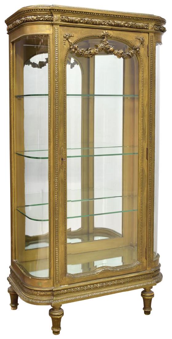 LOUIS XVI STYLE CARVED GILT LIT VITRINE: Louis XVI style carved gilt vitrine, having foliate and garland designs, three glass sides with door to center, the lighted interior having mirrored back and single shelf, rising on turned tapered leg
