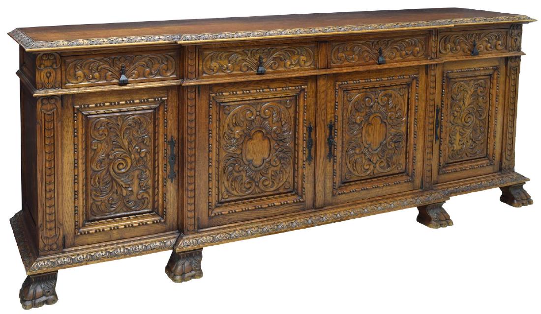 HEAVILY CARVED RENAISSANCE REVIVAL OAK SIDEBOARD: Heavily carved Renaissance Revival oak sideboard, with floral scroll designs, the shaped top over four short drawers and three cabinet doors with shelves to interior, rising on large paw feet, approx 