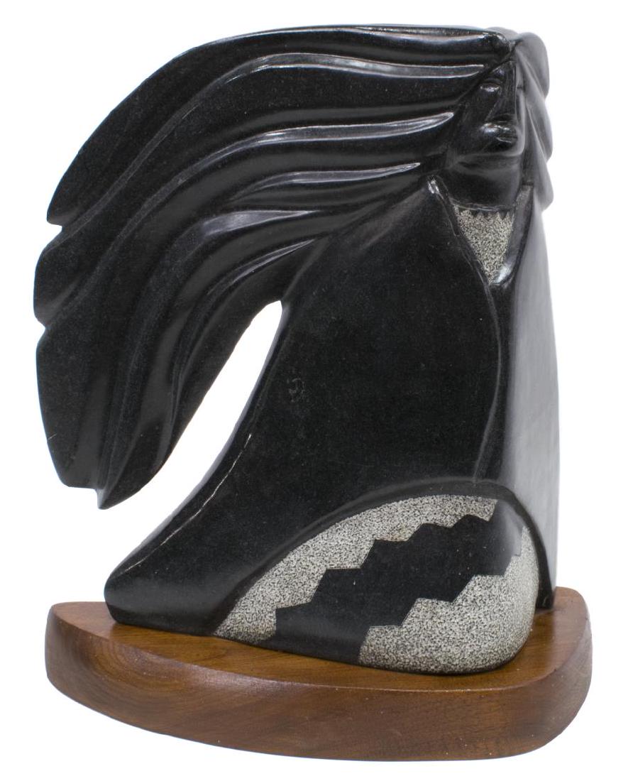 JOHN SUAZO (B.1951)NATIVE AMERICAN STONE SCULPTURE: Native American carved black stone sculpture, Figure with Flowing Hair, signed J. Suazo (John Suazo, American, b.1951) verso, on a shaped wood base, sculpture: 15"h, 13"w, overall: 17"h, 14.25"w, 34.5