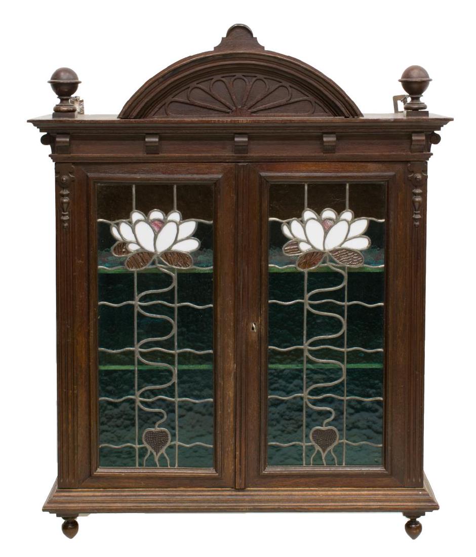 FRENCH OAK STAINED GLASS FRONT WALL CABINET: French oak wall hanging cabinet, 19th c., having turned finials and a rising sun carved pediment over the two-door cabinet with stained and leaded glass fronts, shelves to the interior, approx 39"h, 3