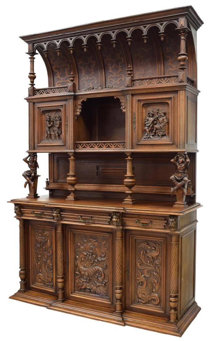HENRI II STYLE HEAVILY CARVED WALNUT SIDEBOARD: Henri II style heavily carved walnut deux corps sideboard, c. 1880's, the corniced top with drop finials and turned supports over top shelf with pierced gallery, above two cabinets with figural carved