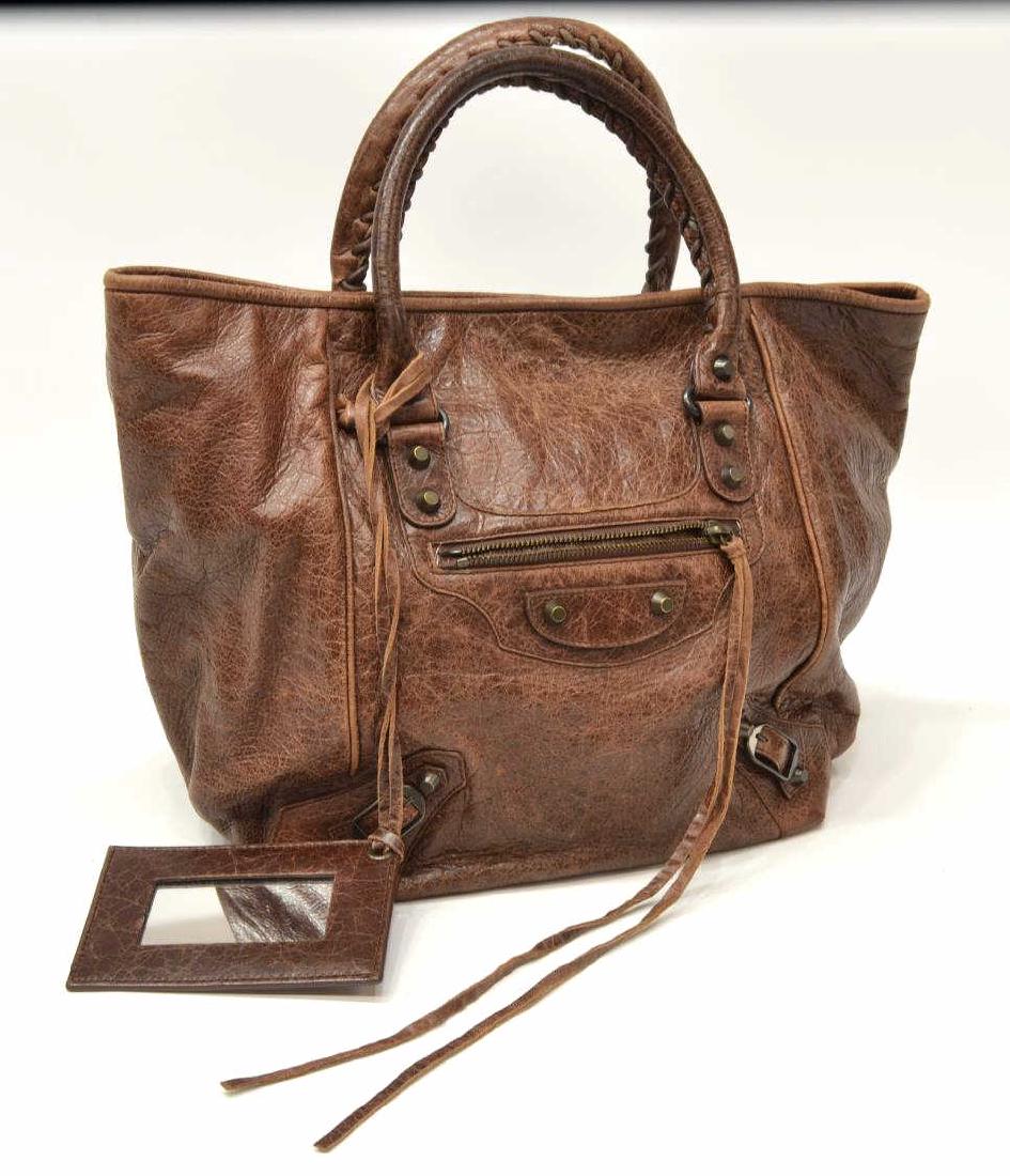 BALENCIAGA MOTOCROSS CLASSIC SUNDAY TOTE: Balenciaga Motocross Classic Sunday Tote, in brown Arena leather, with antiqued brass-tone hardware, dual rolled handles, single pocket at exterior with zip closure, buckle and tassel embellishments a