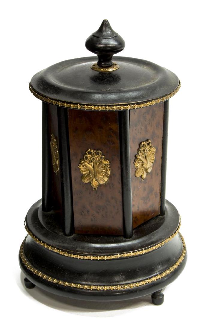 CONTINENTAL GILT METAL MOUNTED BURLED CIGAR BOX: Continental ebonized and burled elm cigar /cigarette box, late 19th/early 20th c., the finialed top with gilt metal trim over swing out doors, interior fitted for cigars, the whole raised on small fee