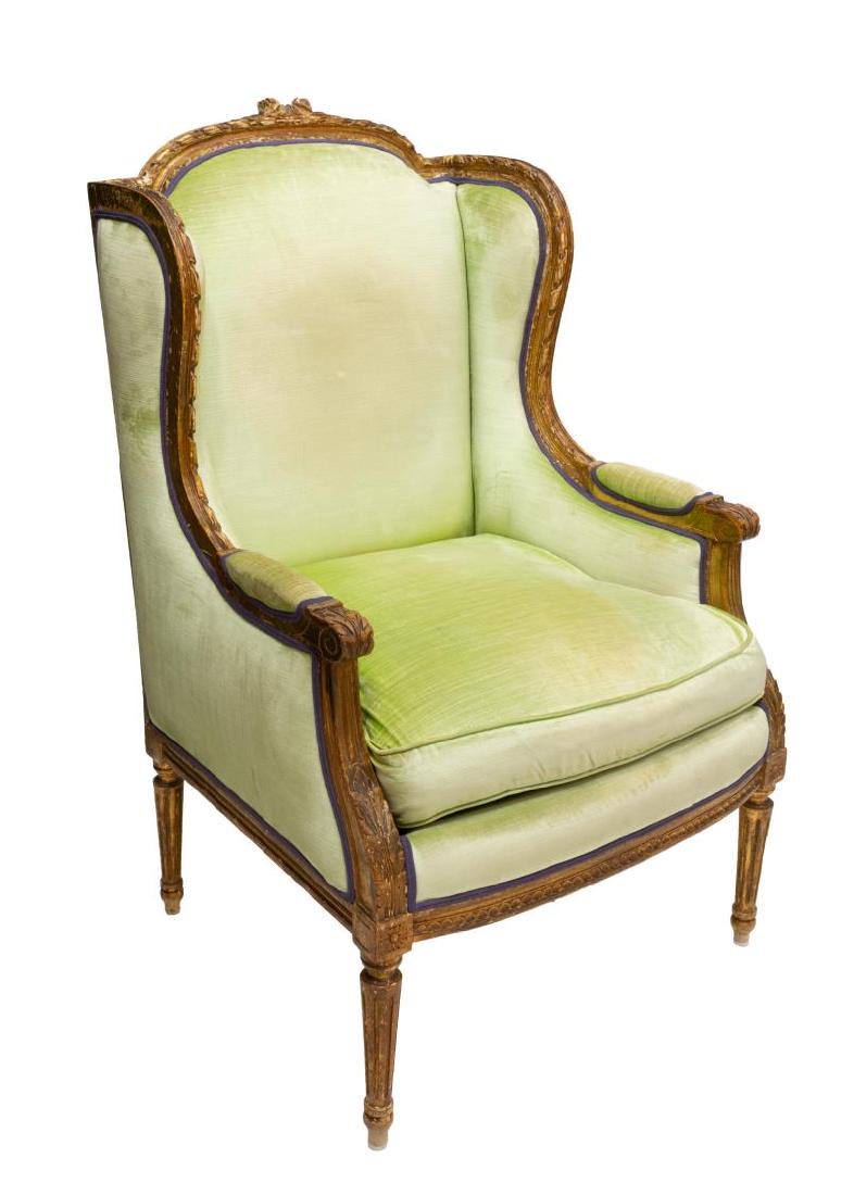 FRENCH LOUIS XVI STYLE PARCEL GILT WINGBACK CHAIR: French Louis XVI style parcel gilt wing chair, 20thc., ribboned crest over padded back and arms, removable cushion seat, all in light green velvet-like upholstery, on fluted legs, approx 42"h, 26.5"w,